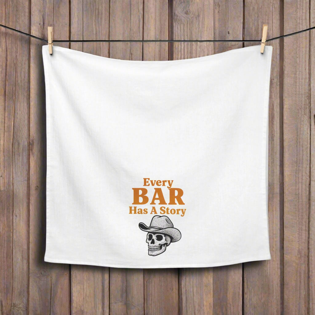 White towel with 'Every Bar Has A Story' text and skull graphic hanging on a line.