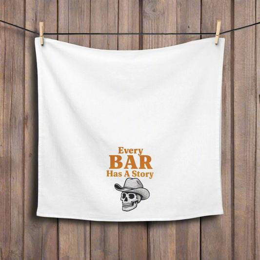 White towel with 'Every Bar Has A Story' text and skull graphic hanging on a line.