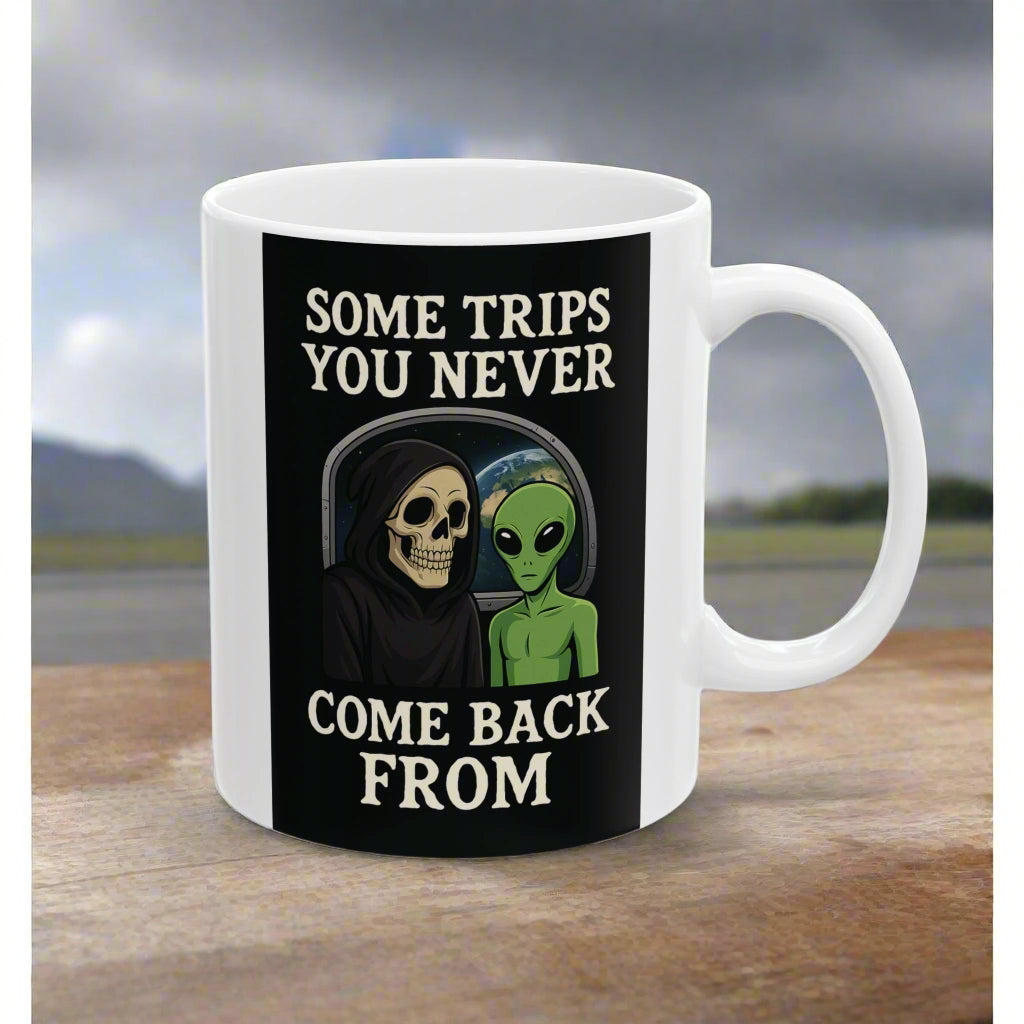 White mug with a black graphic featuring a skull and alien, and text 'Some trips you never come back from' on a white background.
