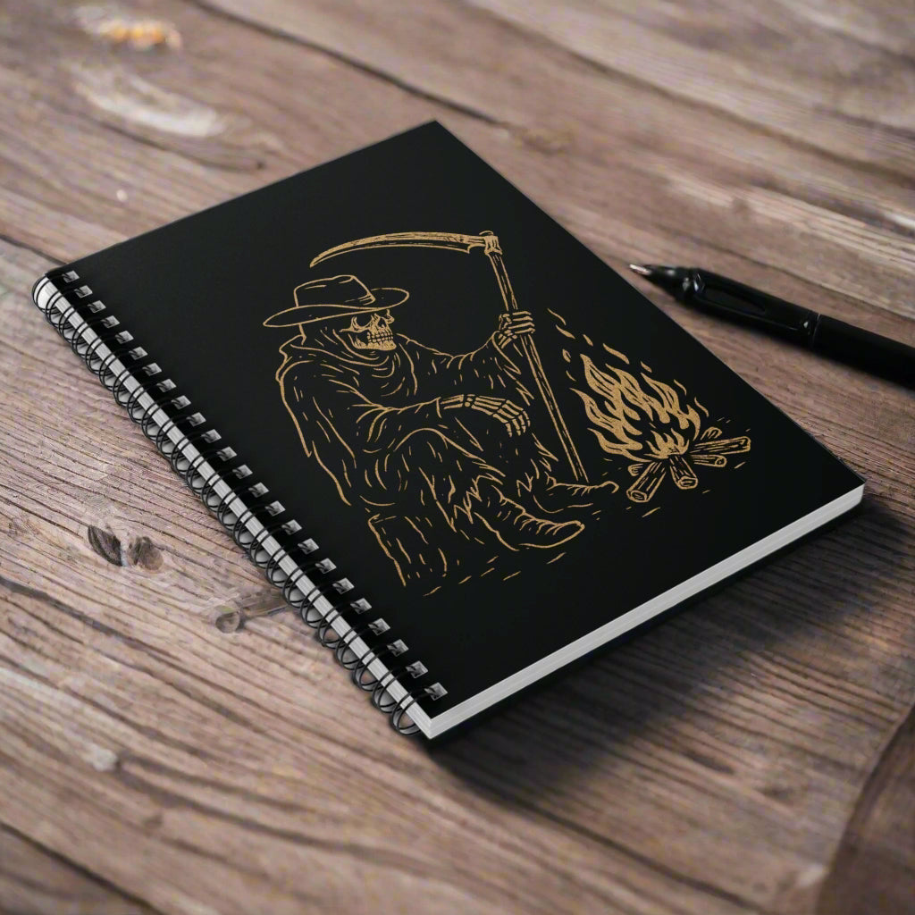 Black notebook with gold illustration of a skeleton holding a scythe and flames on a white background